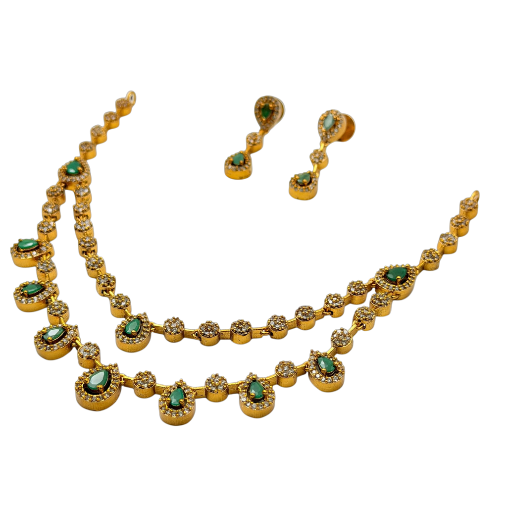 Gold necklace and earrings with green gemstones on a white background