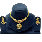 Gold necklace and earrings set on a dark blue stand with a white background