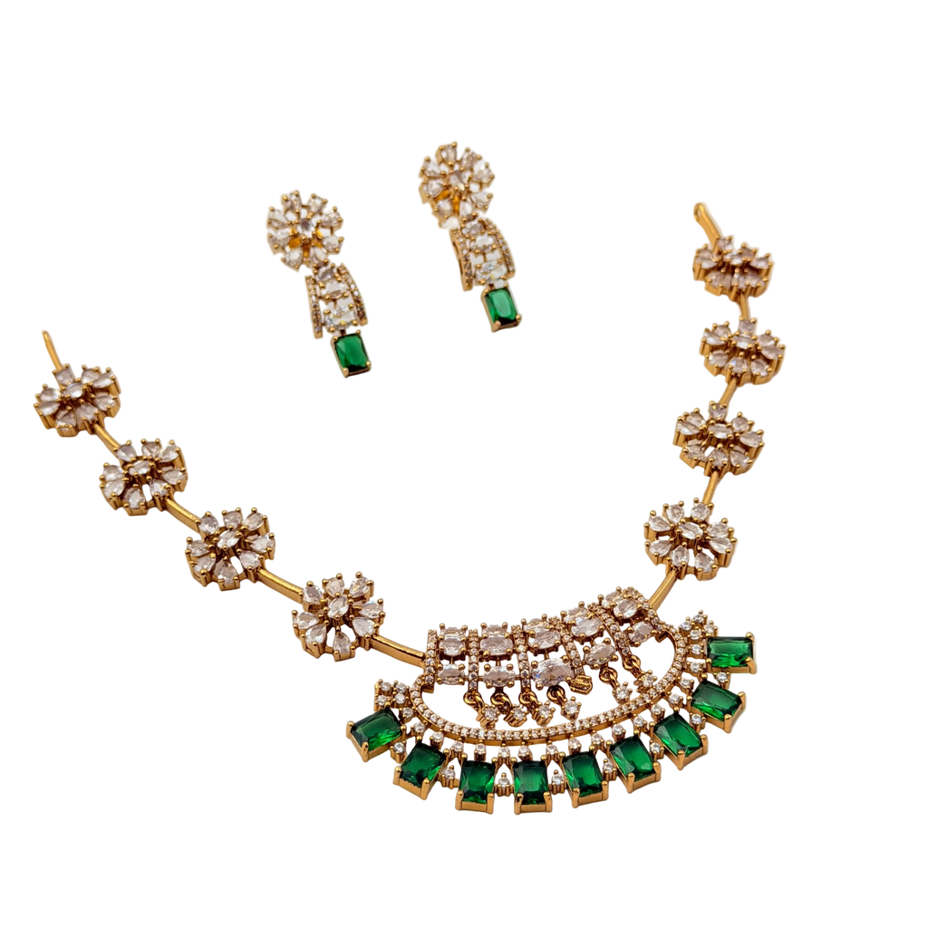 Gold necklace with green gemstones and matching earrings on a white background