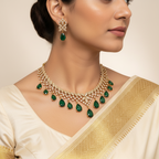 Woman wearing a gold necklace with green gemstones and matching earrings.