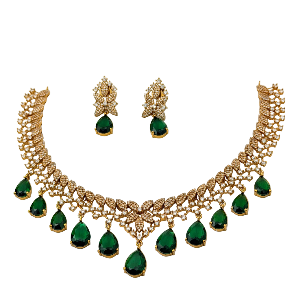 Gold necklace with green gemstones and matching earrings on a white background