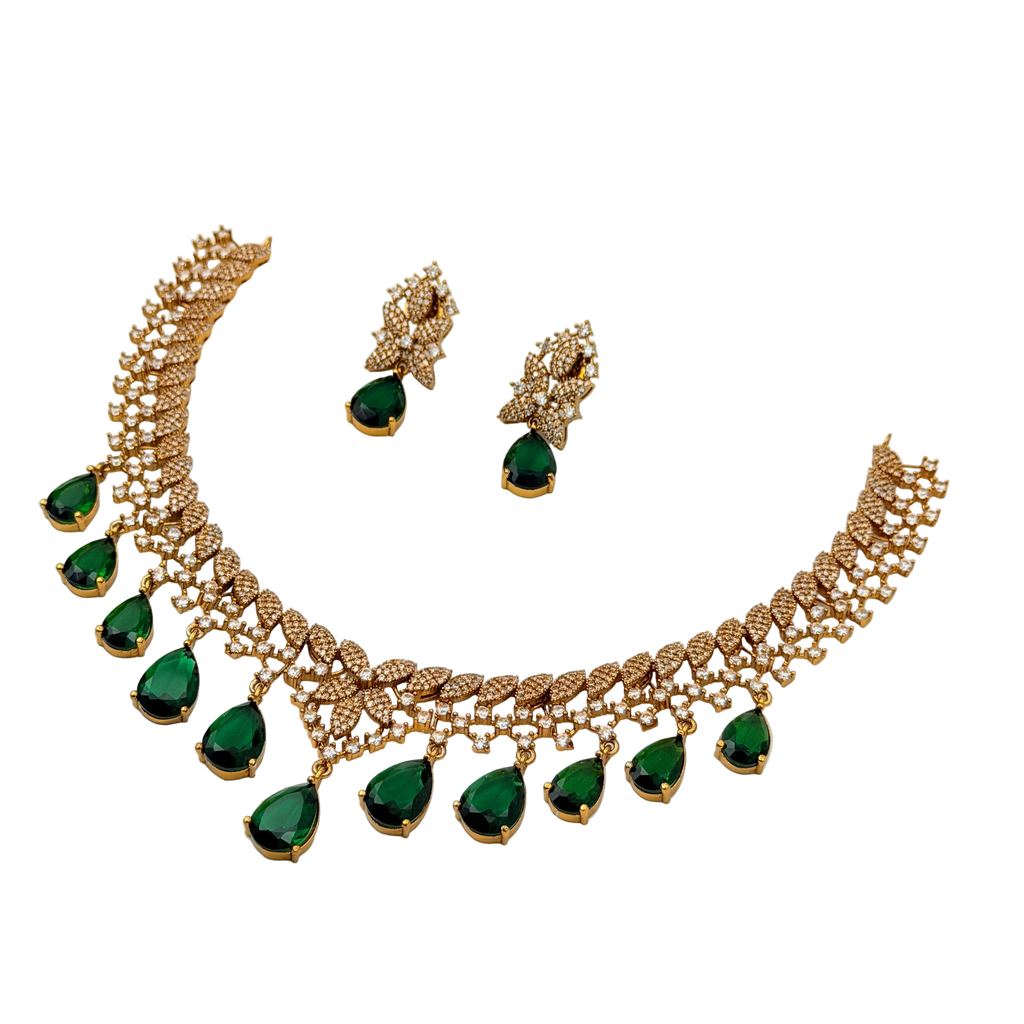 Gold necklace with green gemstones and matching earrings on a white background