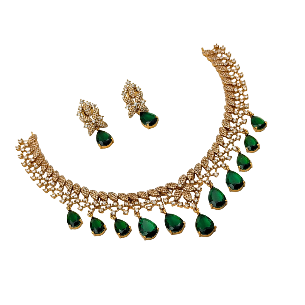 Gold necklace with green gemstones and matching earrings on a white background