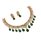 Gold necklace with green gemstones and matching earrings on a white background