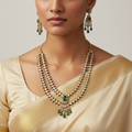 Woman wearing a traditional necklace and earrings with a plain background