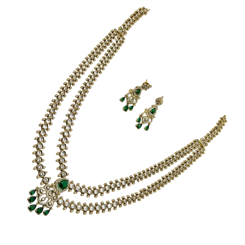 Gold necklace with green gemstones and matching earrings on a white background