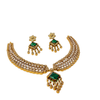 Gold necklace and earrings set with green gemstones on a white background