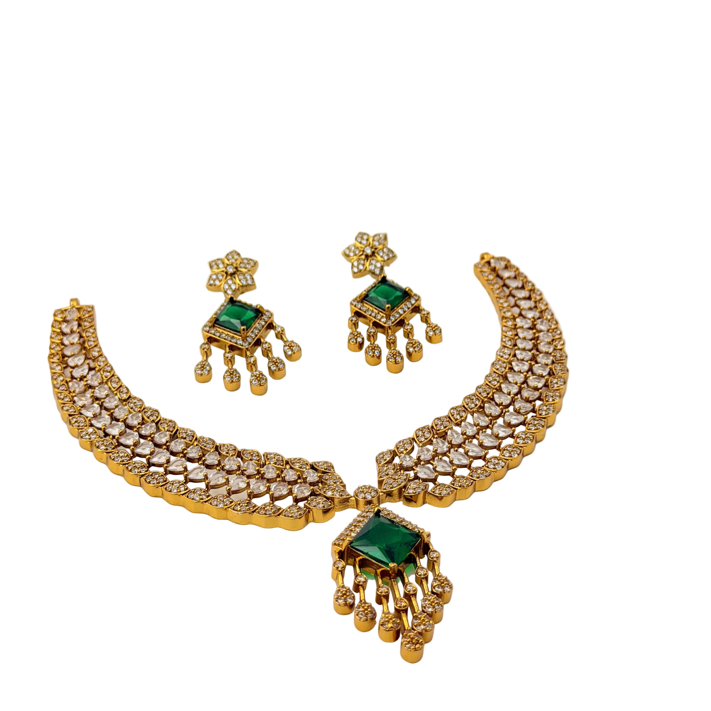 Gold necklace and earrings set with green gemstones on a white background