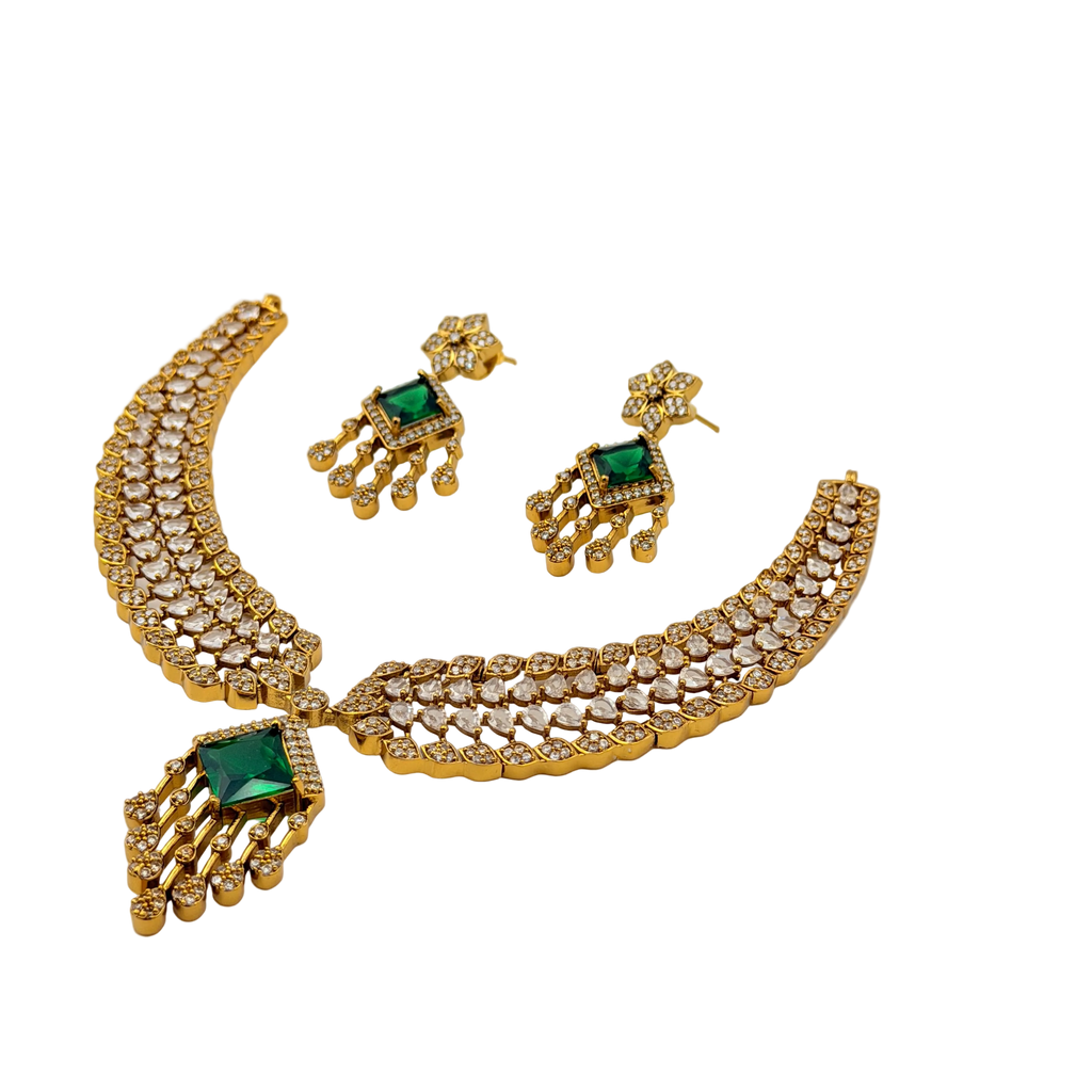 Gold necklace with green gemstones and matching earrings on a white background