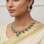 Woman wearing a gold necklace with green gemstones and matching earrings.