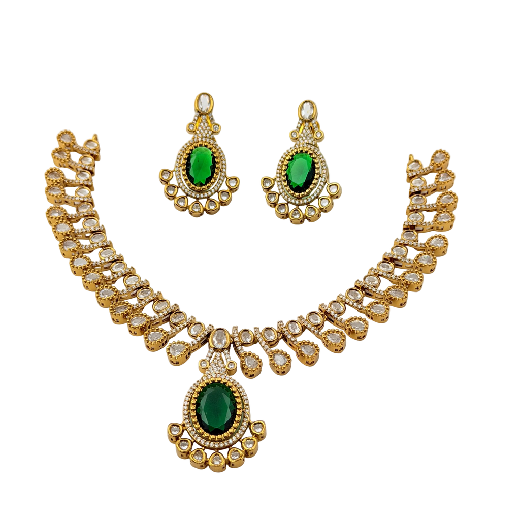 Gold necklace and earrings set with green gemstones on a white background