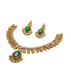 Gold necklace and earrings set with green gemstones on a white background