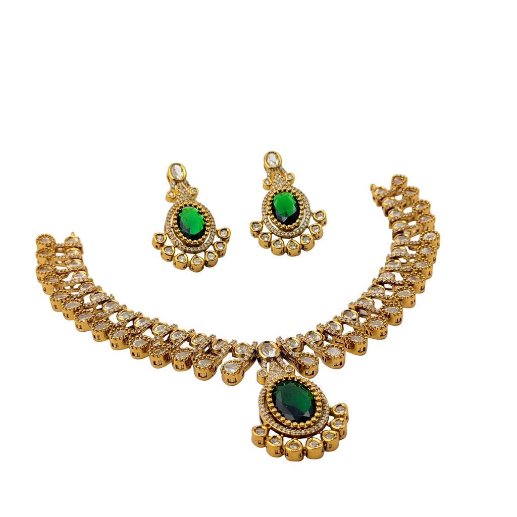 Gold necklace and earrings with green gemstones on a white background