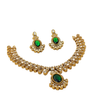 Gold necklace and earrings with green gemstones on a white background