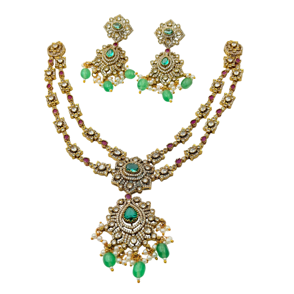 Gold necklace with green and red stones on a white background