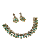 Jewelry set with necklace and earrings featuring green gemstones on a white background
