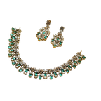 Jewelry set with necklace and earrings featuring green gemstones on a white background