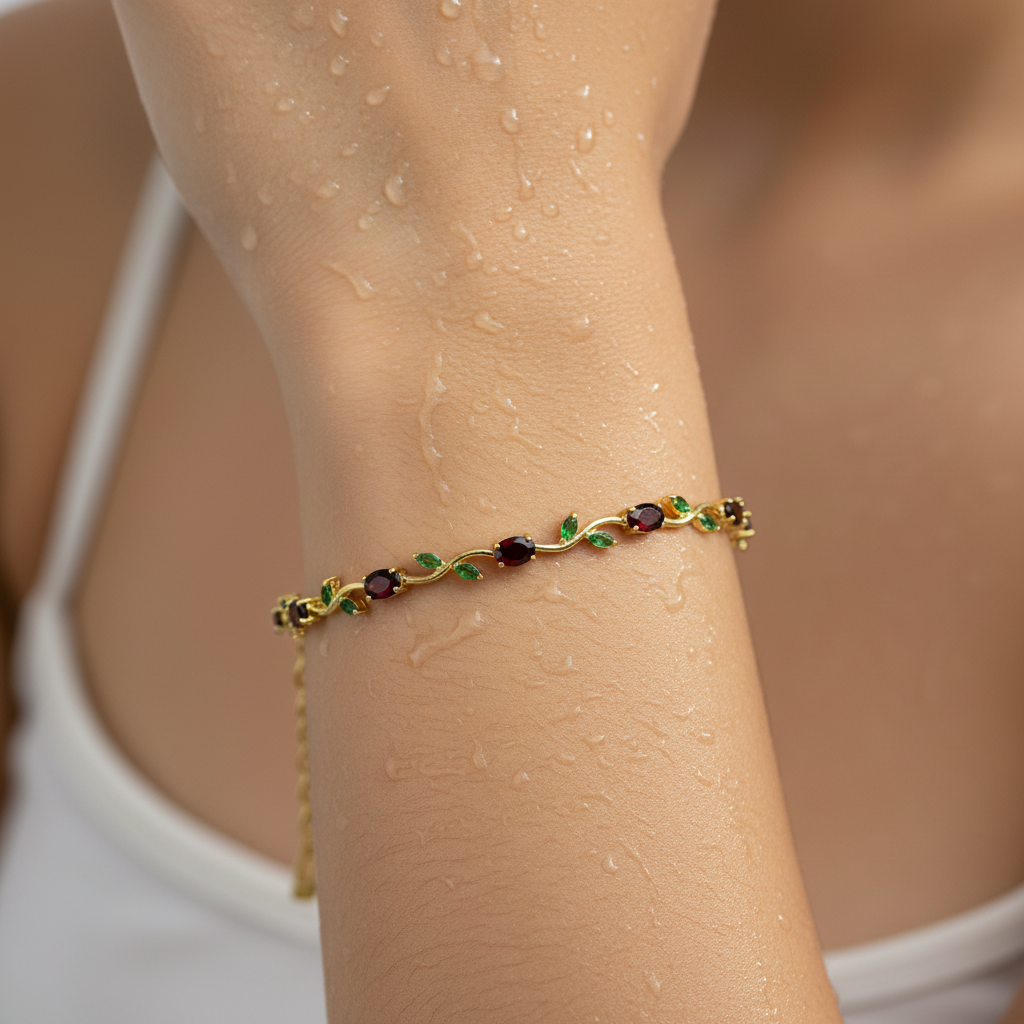 Gold bracelet with gemstones on a wrist against a neutral background