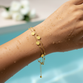 Gold-toned double chain bracelet with beads and polished disc charms, worn on wrist