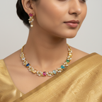 Gold multicolour crystal vine necklace set with pearl-drop earrings, flat-lay on cushion