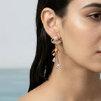 Gold-plated crystal tassel drop earring with fan motif top, on-ear close-up showing pave stone detailing and teardrop dangles