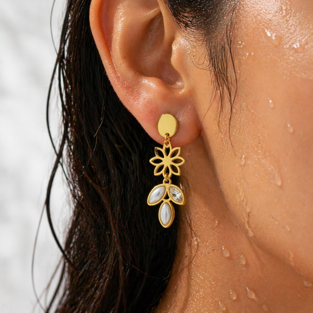 Gold floral earring worn by a person with a blurred background
