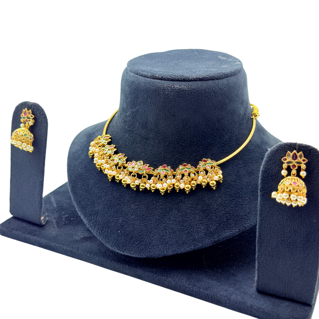 Gold necklace and earrings set on a blue velvet stand