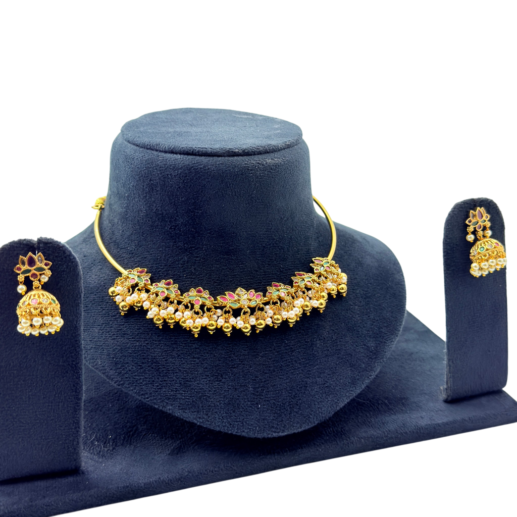 Gold necklace and earrings set on a blue velvet stand