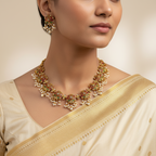 Woman wearing a gold and pearl necklace with a beige saree on a neutral background