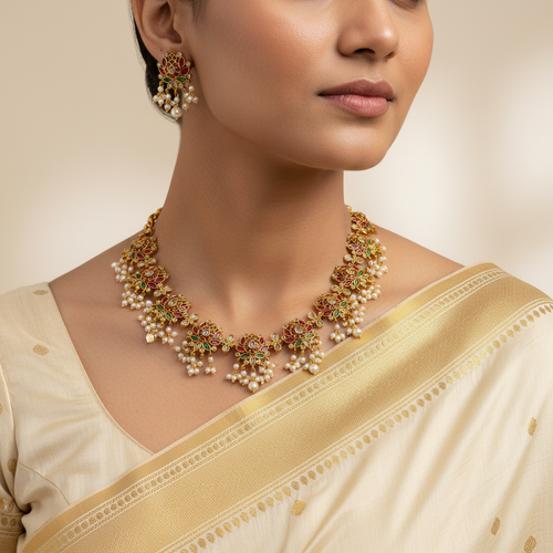 Woman wearing a gold and pearl necklace with a beige saree on a neutral background