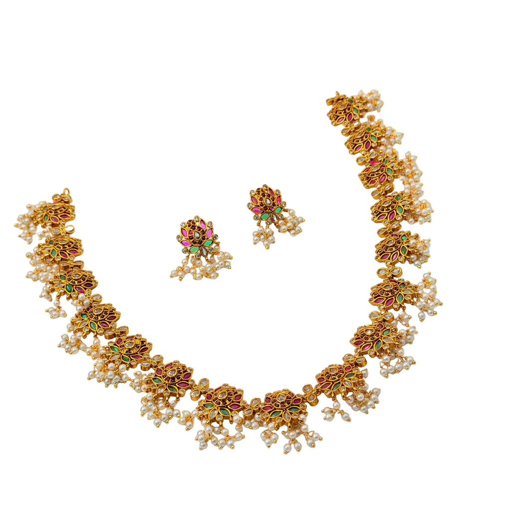Gold necklace with floral designs and colorful gemstones on a white background