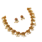 Gold necklace with floral designs and colorful gemstones on a white background
