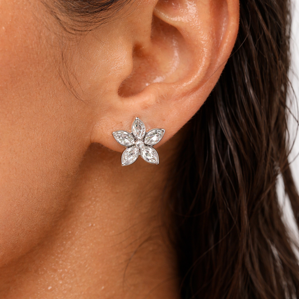 Close-up of an ear wearing a flower earring with hair partially visible.
