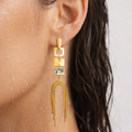Gold earring with geometric design worn by a person