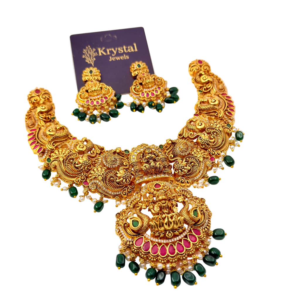 Ornate gold necklace with green and red accents on a white background, featuring Krystal Jewels packaging.