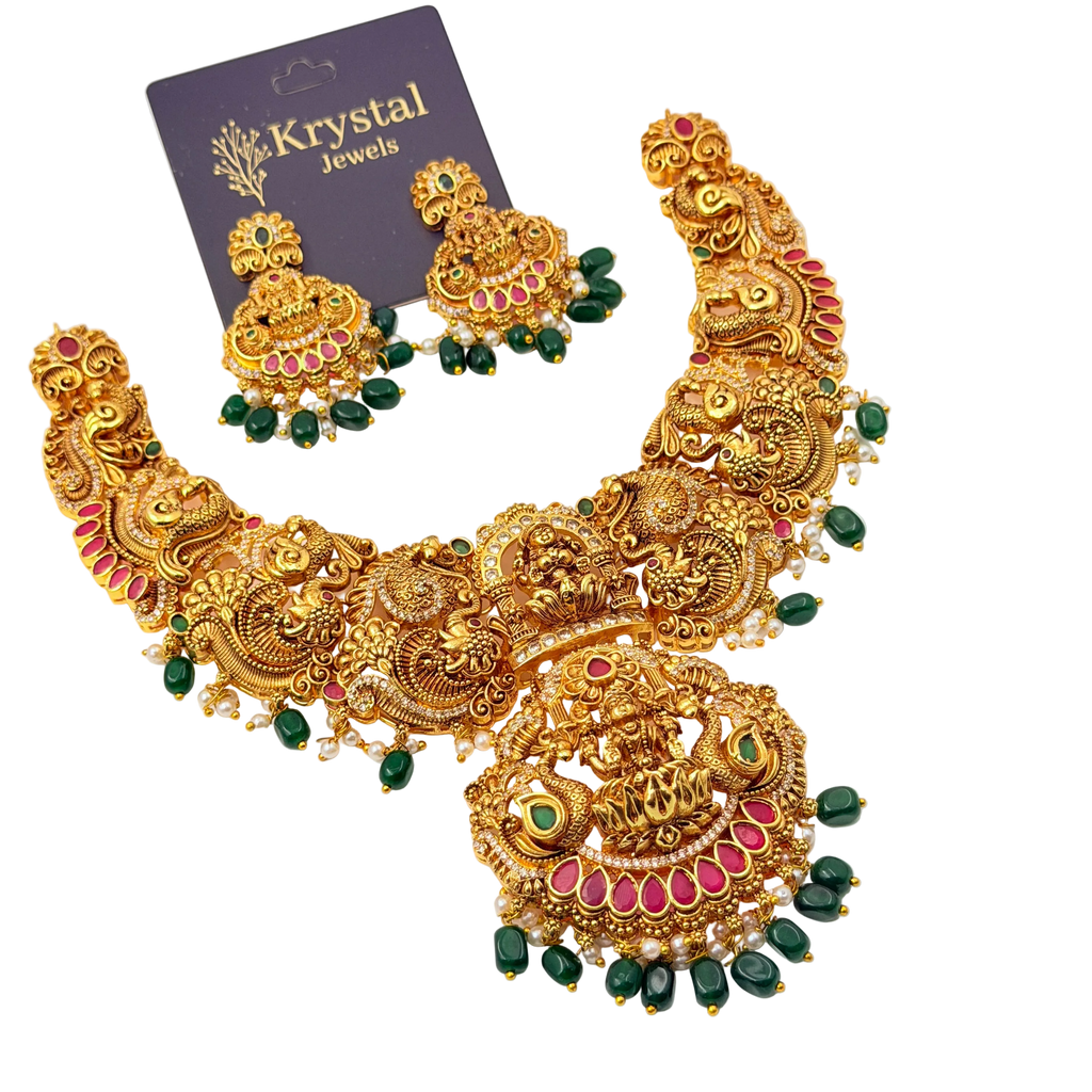 Gold necklace with green and red stones on a white background, branded as Krystal Jewels.