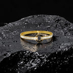 Gold bracelet with black center on a dark textured surface
