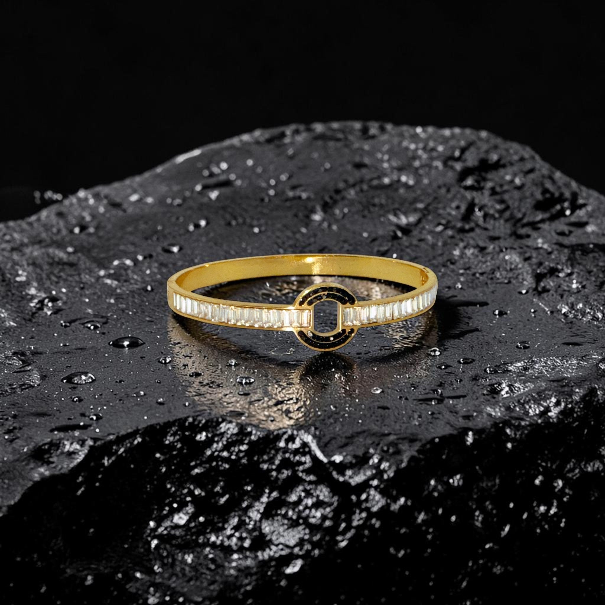 Gold bracelet with black center on a dark textured surface