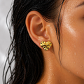 Close-up of a person wearing a gold heart-shaped earring with black accents.