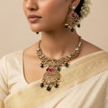 Woman wearing a gold necklace and earrings with a beige saree on a beige background