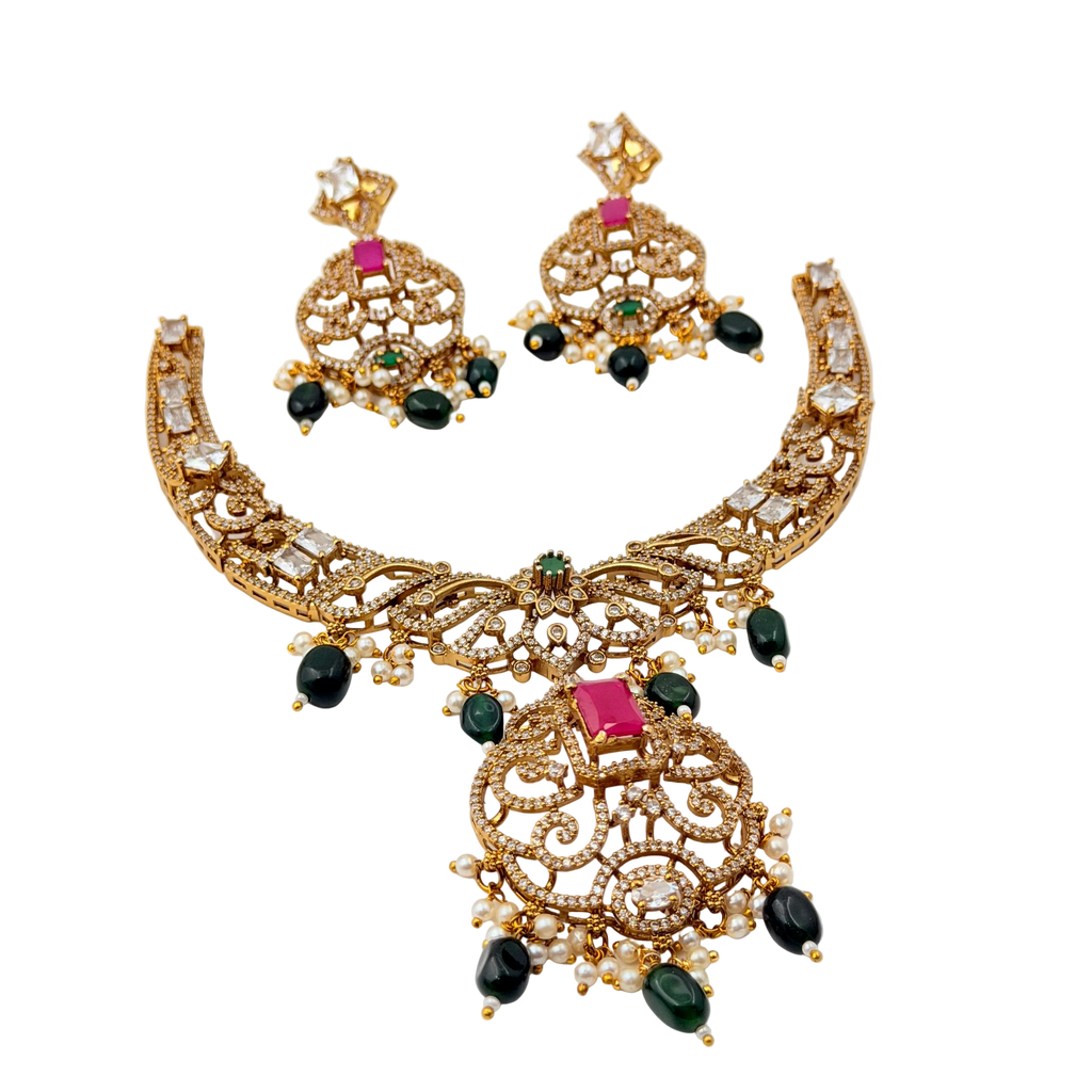 Gold necklace and earrings set with gemstones on a white background