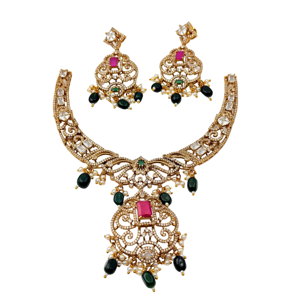 Gold necklace and earrings set with gemstones on a white background