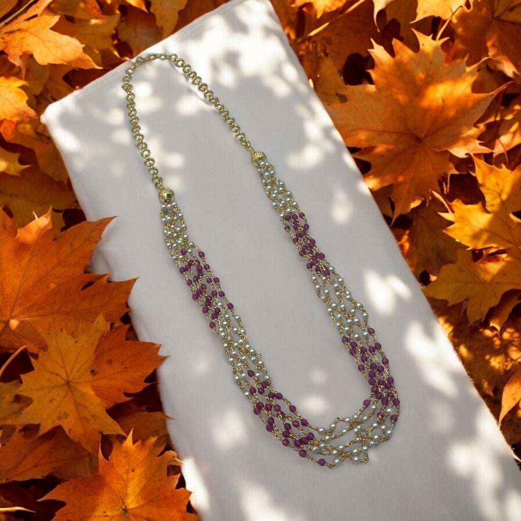 Gold-plated multi-strand beaded necklace with ruby-toned beads and white pearls, flat-lay detail shot