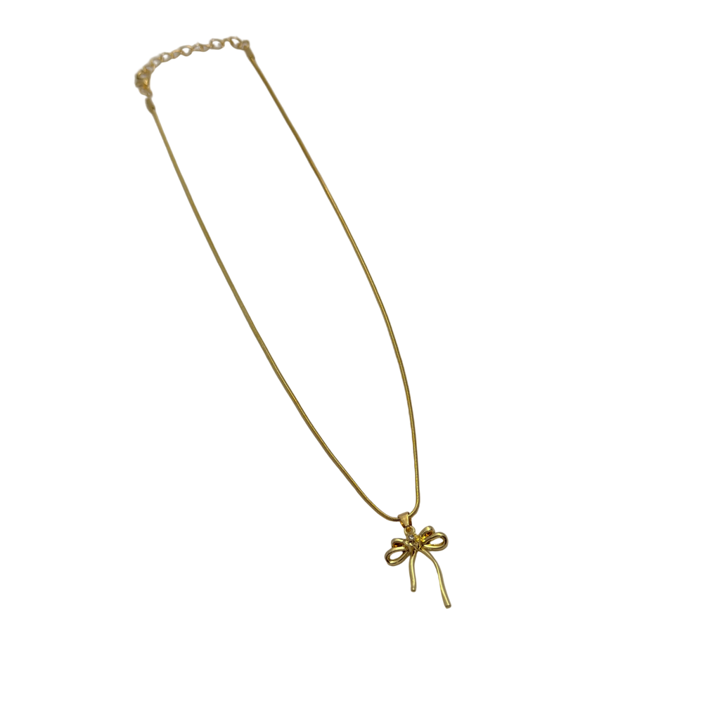 Close-up of gold-tone bowknot ribbon pendant with single round clear crystal center accent