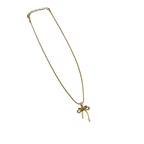 Close-up of gold-tone bowknot ribbon pendant with single round clear crystal center accent