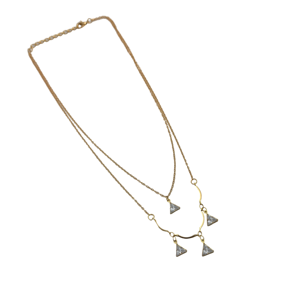 Gold-tone double-layered necklace with wavy bar and four trillion-cut crystal charms, angled flat lay on black background