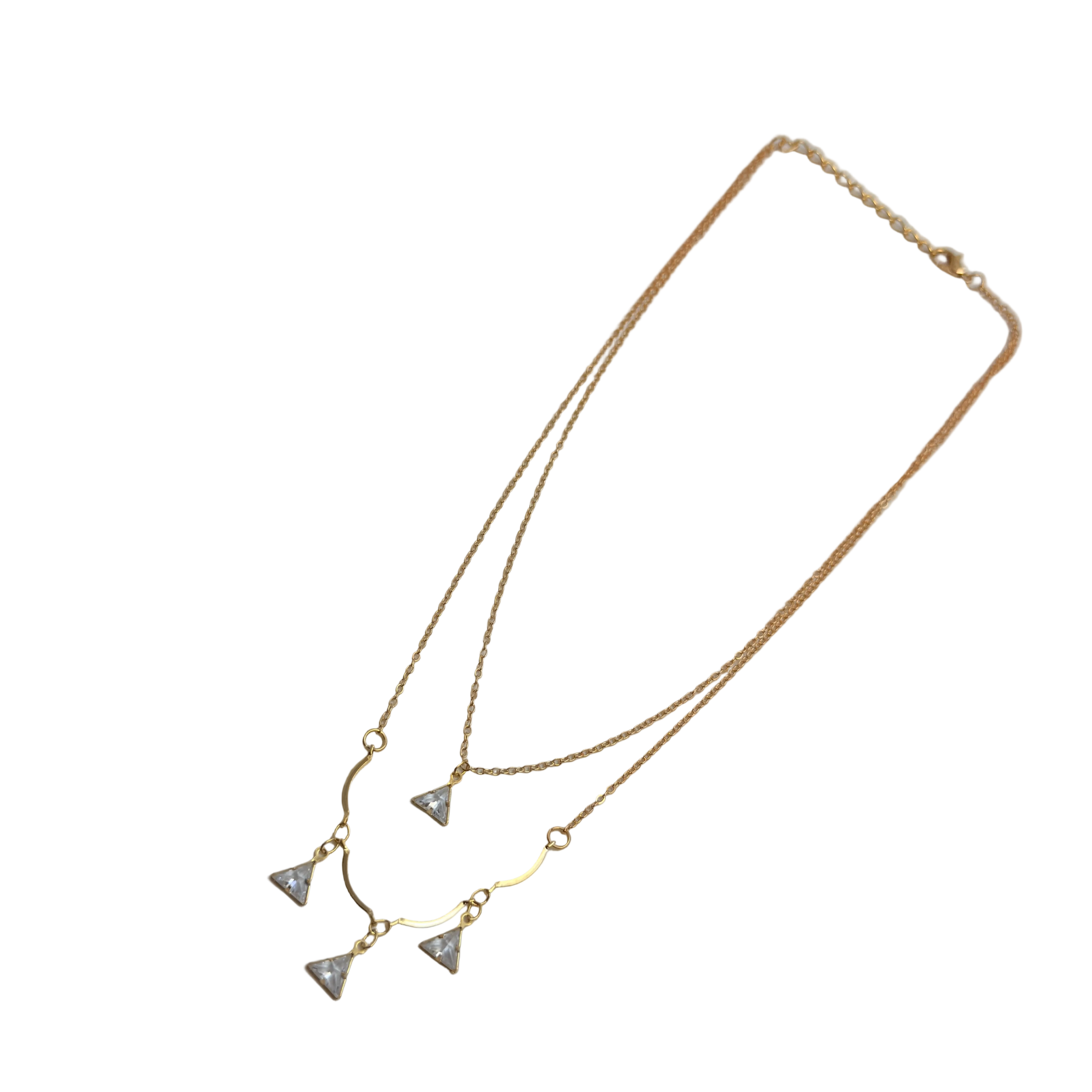 Gold-tone double-layered necklace with wavy bar and four trillion-cut crystal charms, angled flat lay on black background