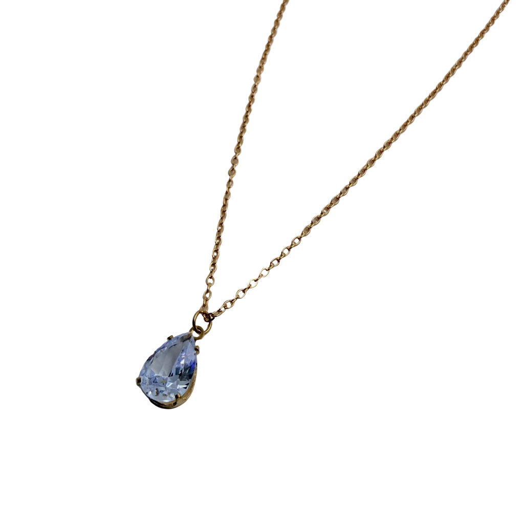 Gold-tone pendant necklace with pear-cut clear crystal solitaire, close-up on the multi-prong pendant setting