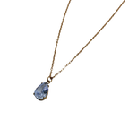 Gold-tone pendant necklace with pear-cut clear crystal solitaire, close-up on the multi-prong pendant setting