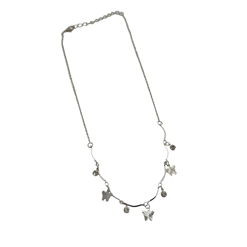 Polished silver butterfly charm necklace with clear crystal accents, worn on model at the beach